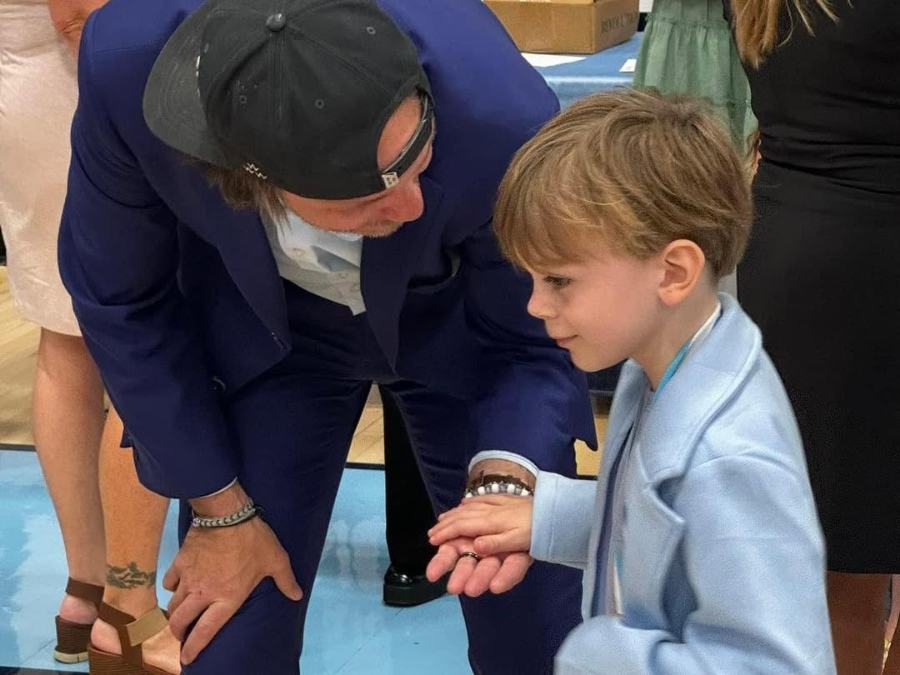 A small boy in a blue suit being greeted at the studio