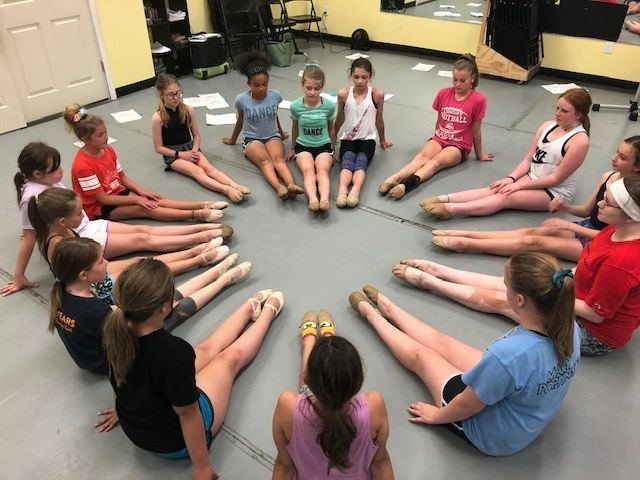 A combo class of young dancers lined up at the barre