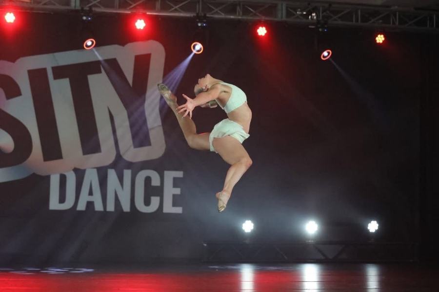 A dancer mid leap on the competition stage under the lights