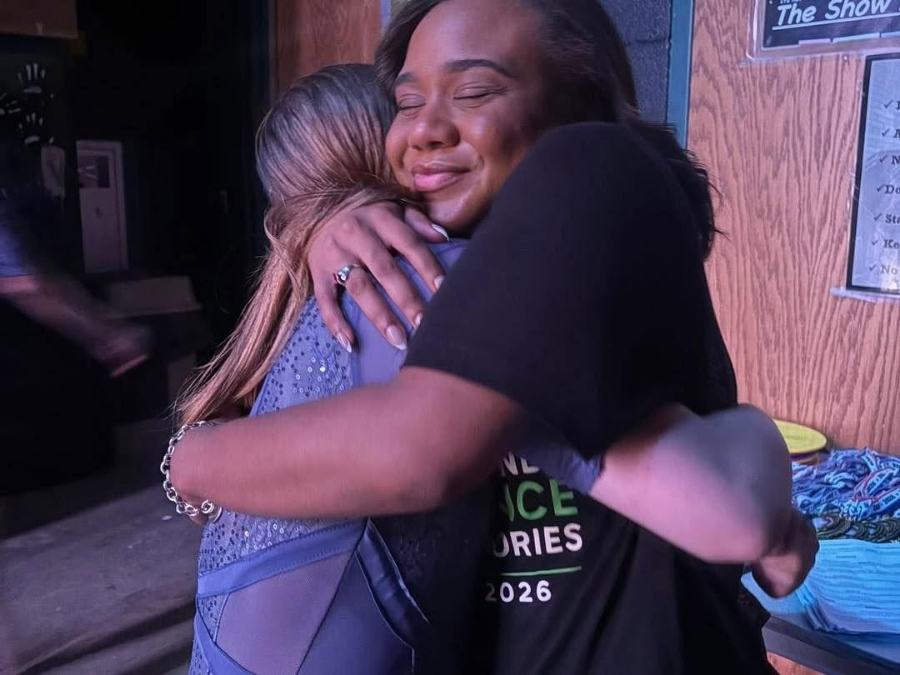 Two dancers hugging backstage after a performance