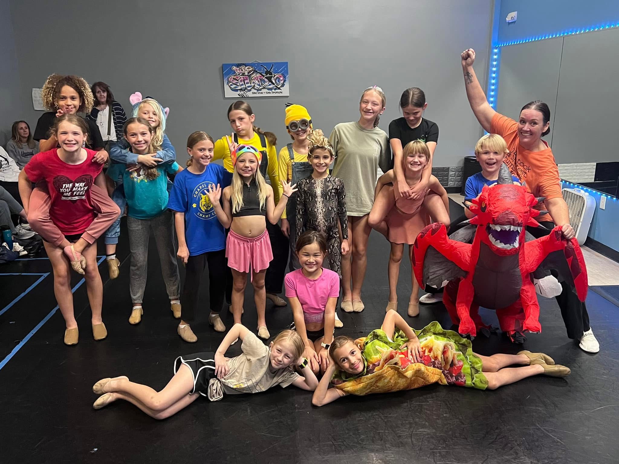 A whole class in Halloween costumes piled together for a photo with their teacher