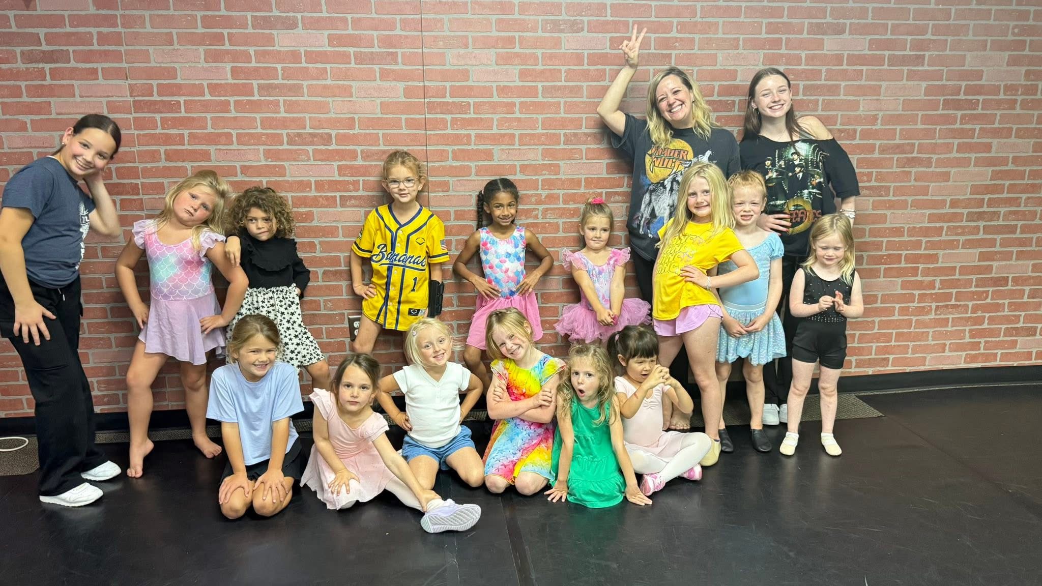 The youngest dancers lined up along the brick wall in class clothes, pulling faces for the camera
