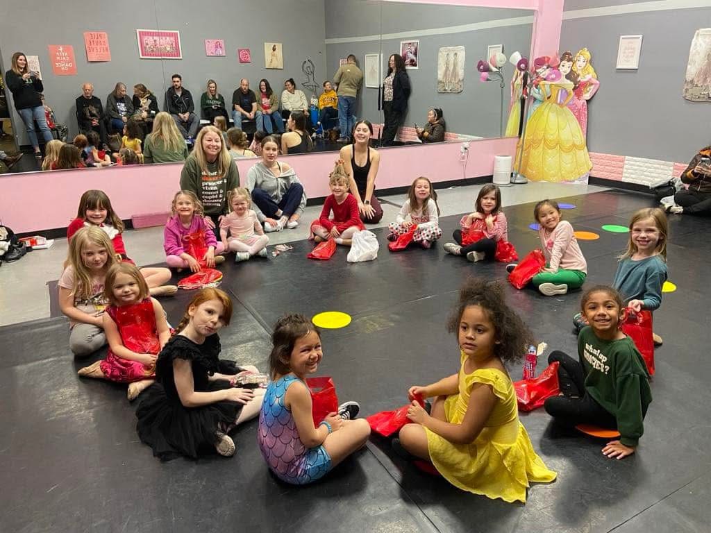 The youngest dancers sitting in a circle on the studio floor with party bags