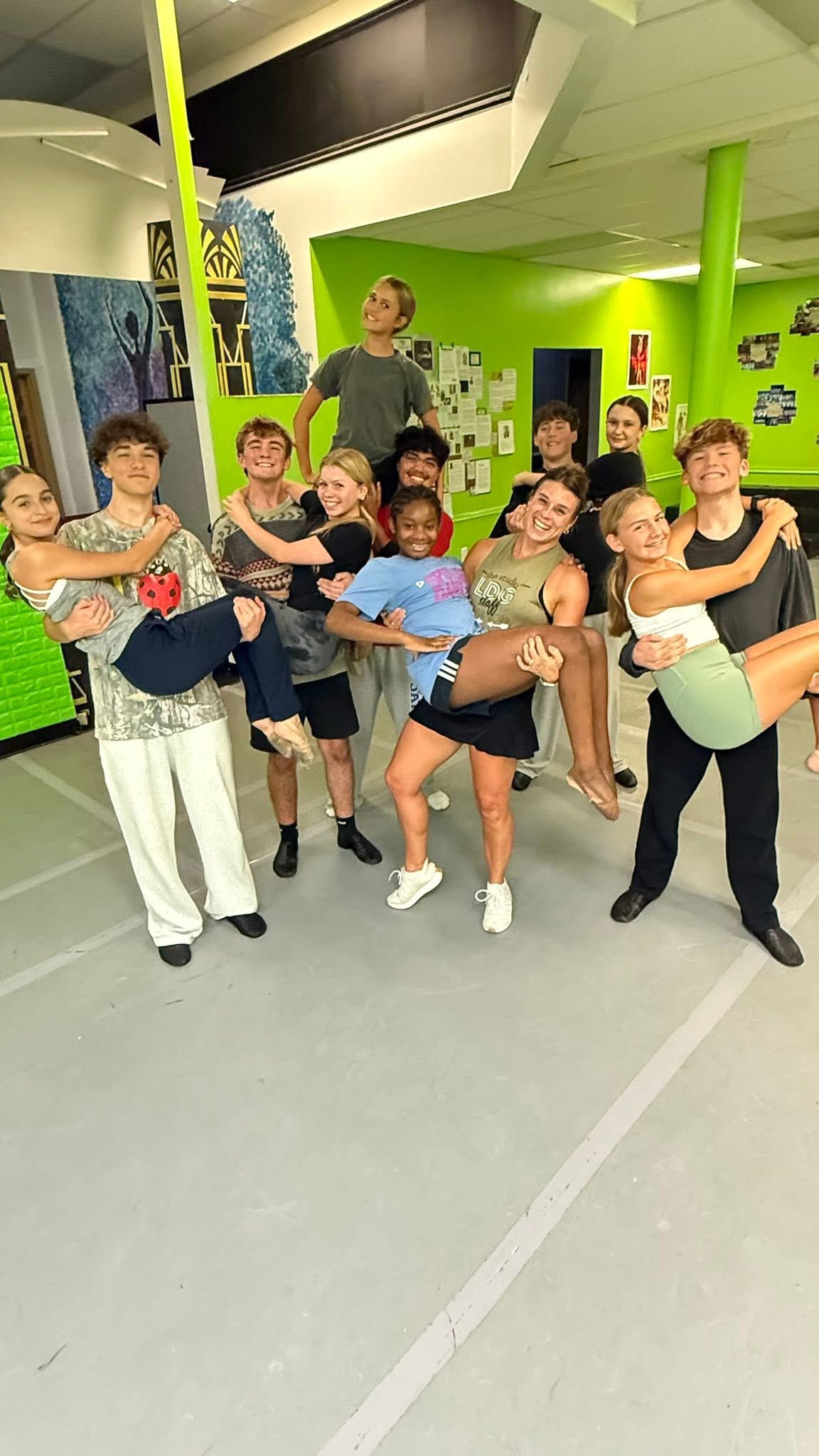 Teen dancers lifting each other and laughing together in the studio